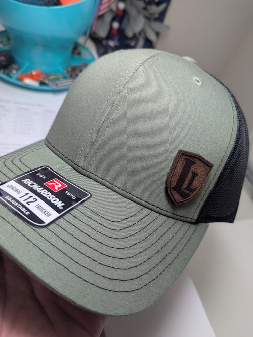 Green baseball cap with Richardson logo and brown leather patch on a blurred background